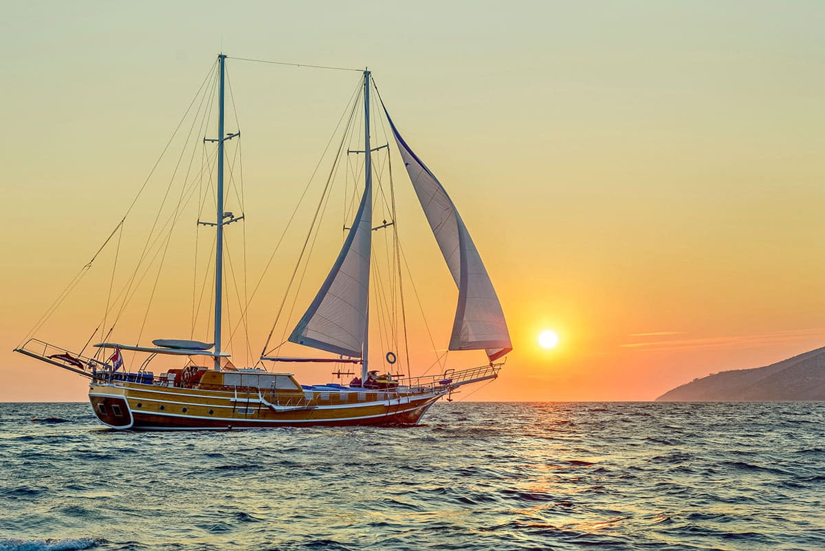 Luxurious large wooden ship sailing in front of a sunset