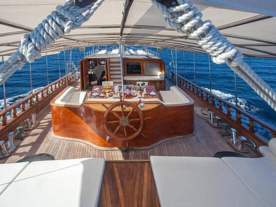 Exterior ship details of a wooden steering wheel and outdoor dining area