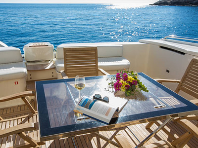 Outdoor furniture on the main deck of a Ferretti 591 yacht out at sea on a sunny summer day